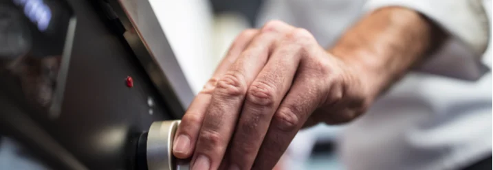 Hand dreht einen Knopf am Herd